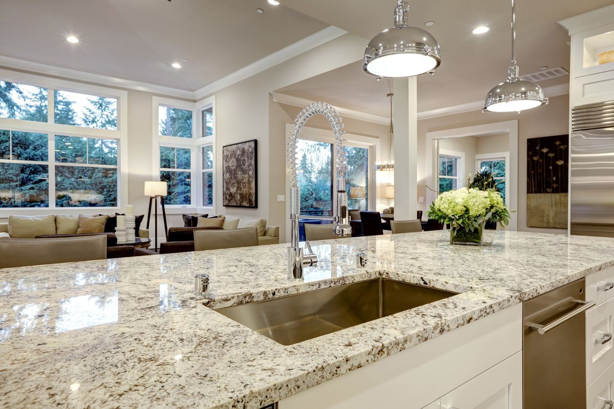 A kitchen with granite counter tops and a stainless steel sink.