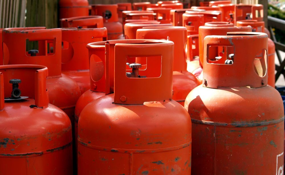 Rows of Orange Red Gas Cylinders Stacked Closely Together Outdoors — Kuranda Gas & Supplies In Mossman, QLD