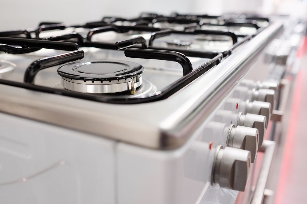 Close-Up of A White and Silver Gas Stove with Black Burner Grates and Control Knobs — Kuranda Gas & Supplies In Gordonvale, QLD