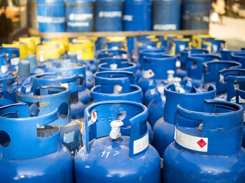 Blue Propane Tanks, Some with White Bands and Red Hazard Symbols, Stacked in A Group — Kuranda Gas & Supplies In Cairns, QLD