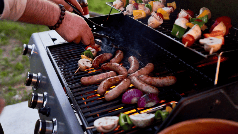 Person Grilling Sausages and Skewers on A Barbecue — Kuranda Gas & Supplies In Koah, QLD