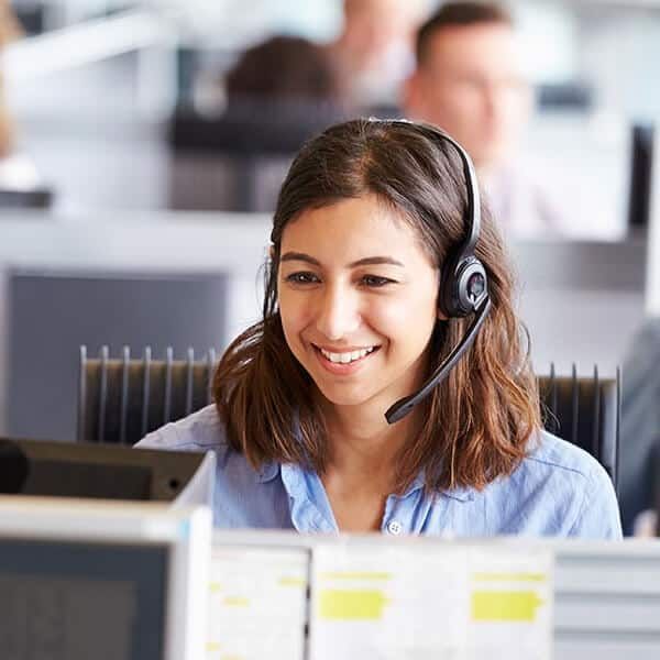Woman with Headset Smiles While Working at A Computer in An Office Setting — Kuranda Gas & Supplies In Koah, QLD