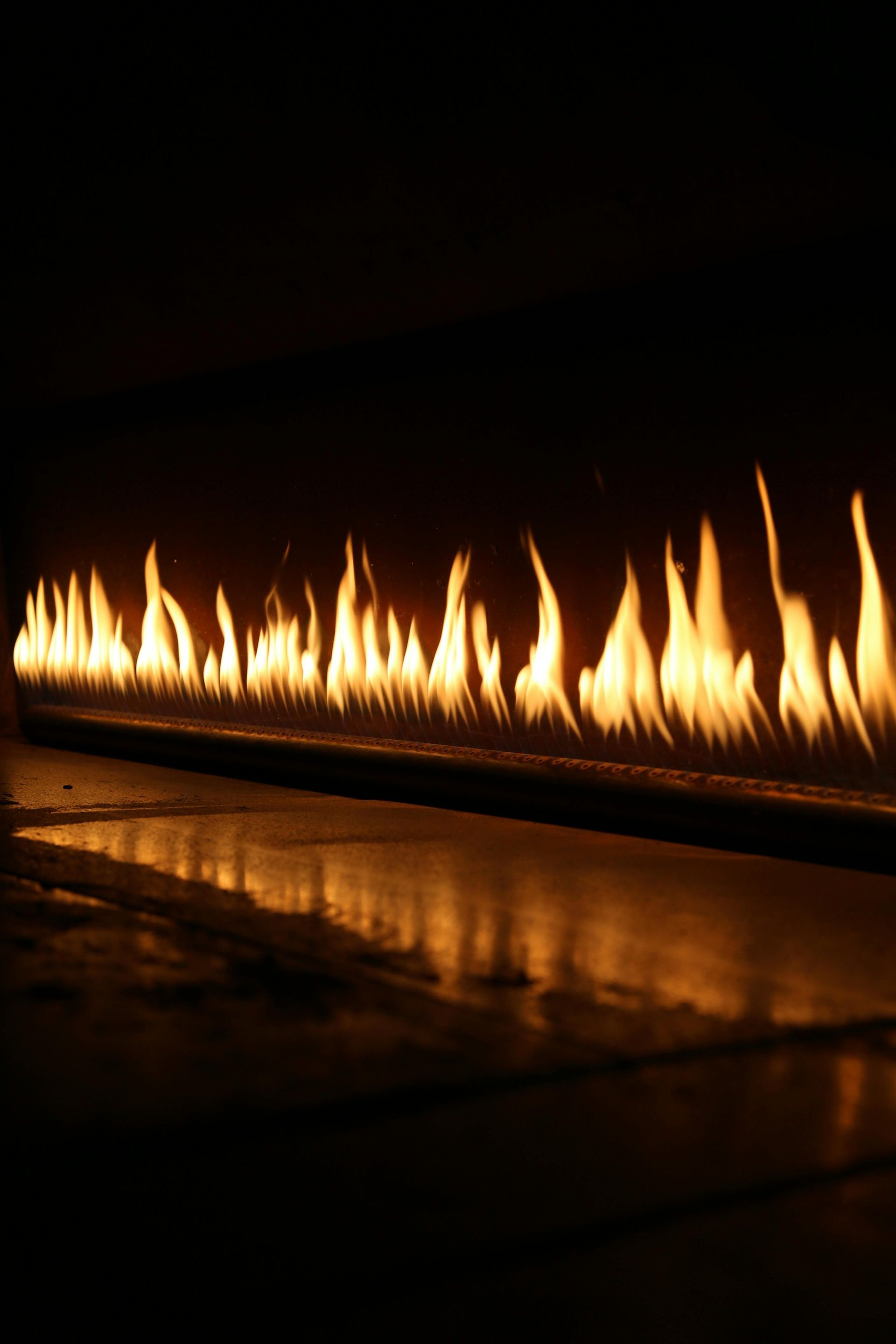 Flames of An Orange Fire Dancing in A Linear Row Against a Dark Background, Reflecting Below — Kuranda Gas & Supplies In Koah, QLD