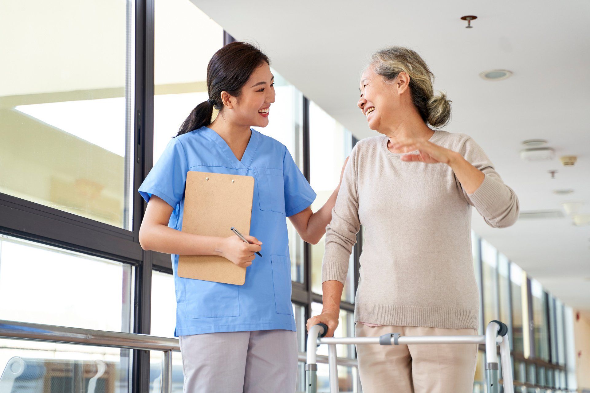 A nurse is helping an elderly woman walk with a walker.