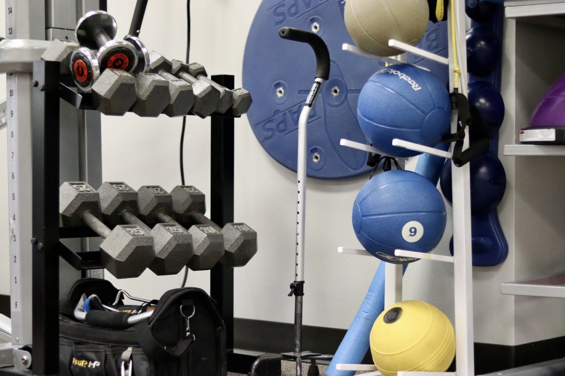A gym with dumbbells , medicine balls , and a cane
