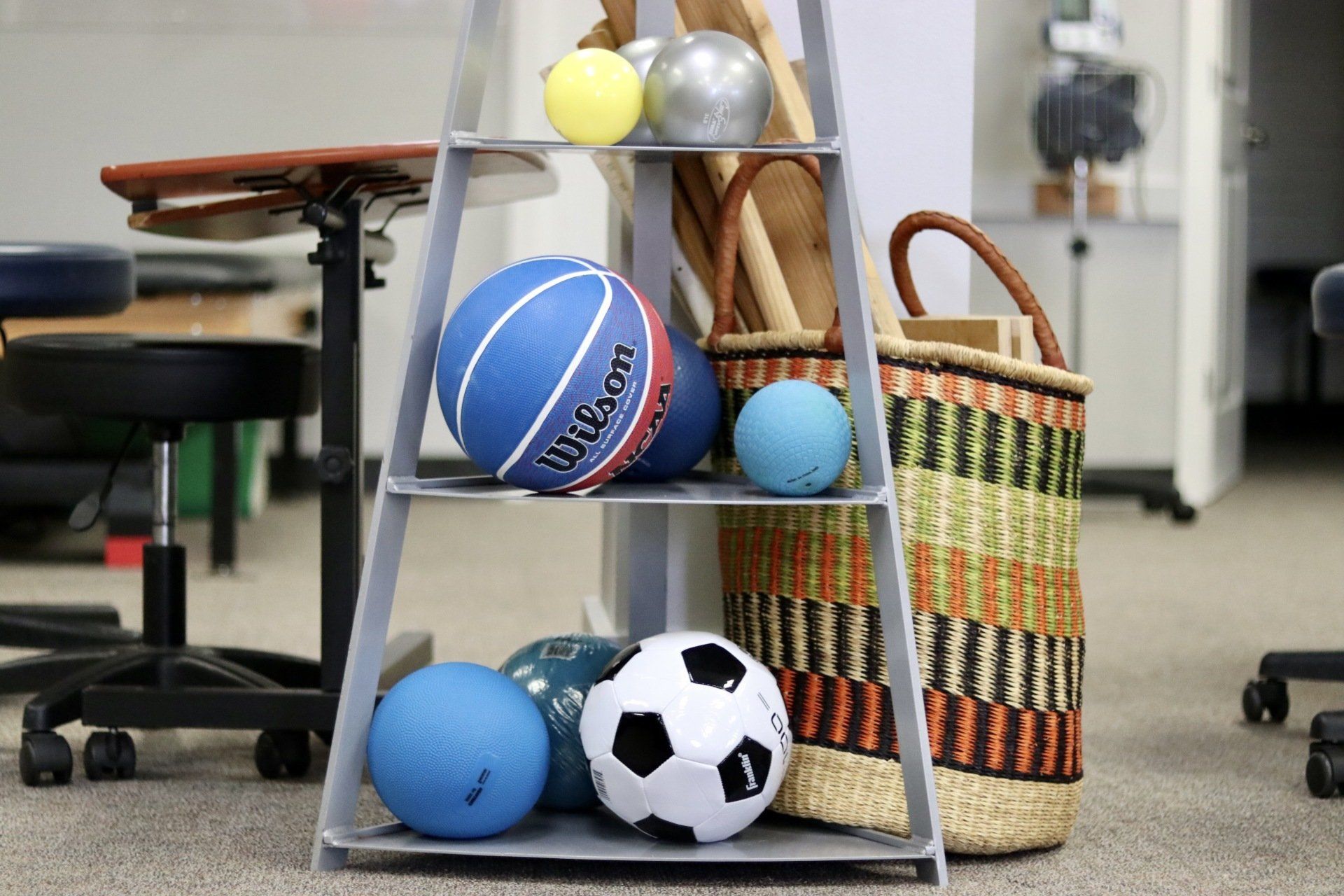 a shelf filled with balls including a basketball and a soccer ball .