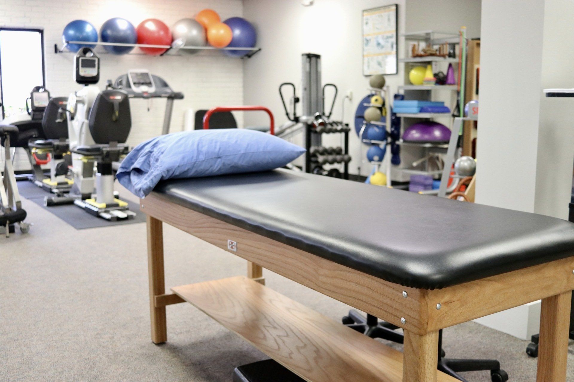a physical therapy room with a bed and exercise equipment