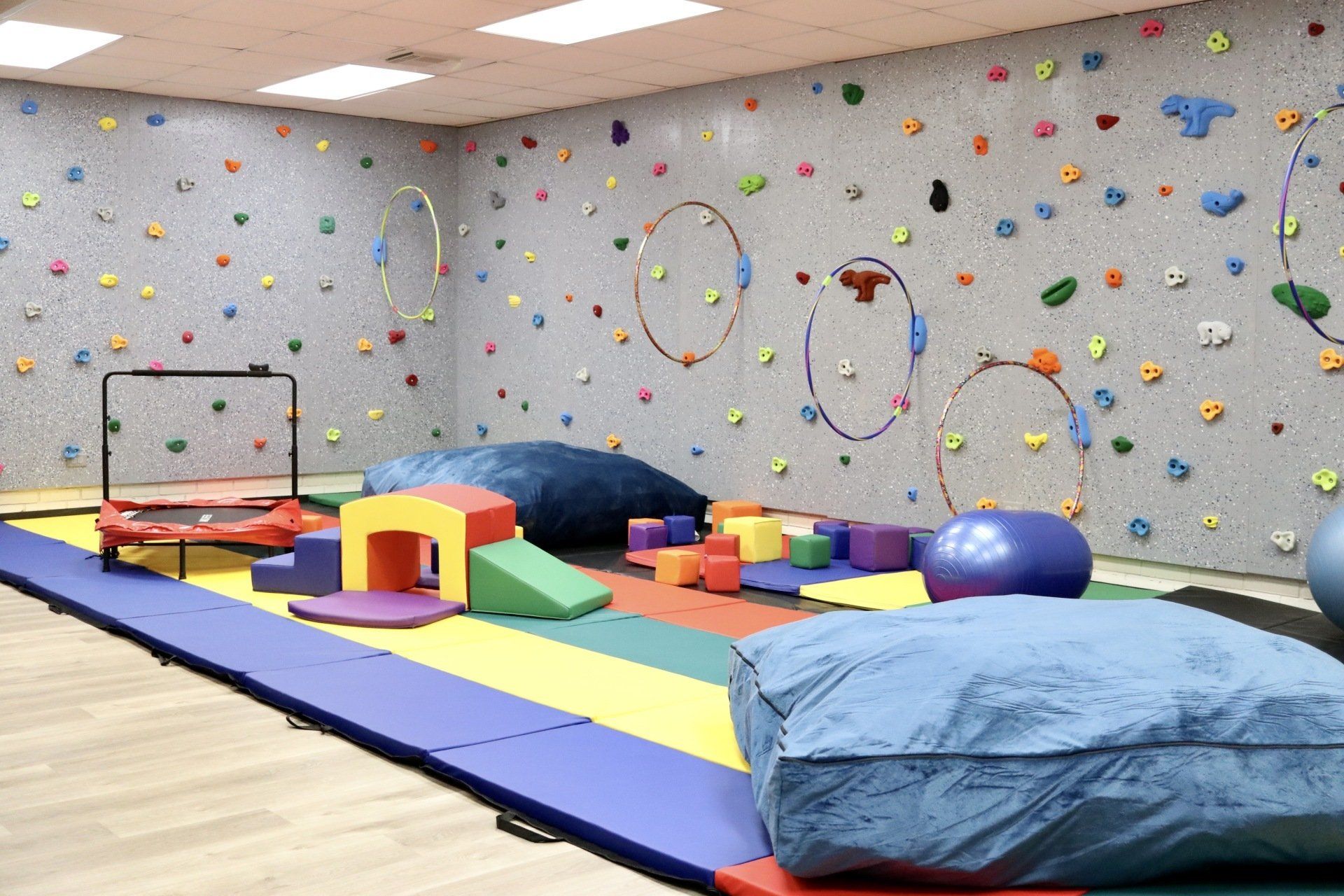 a gym with a climbing wall and toys on the floor