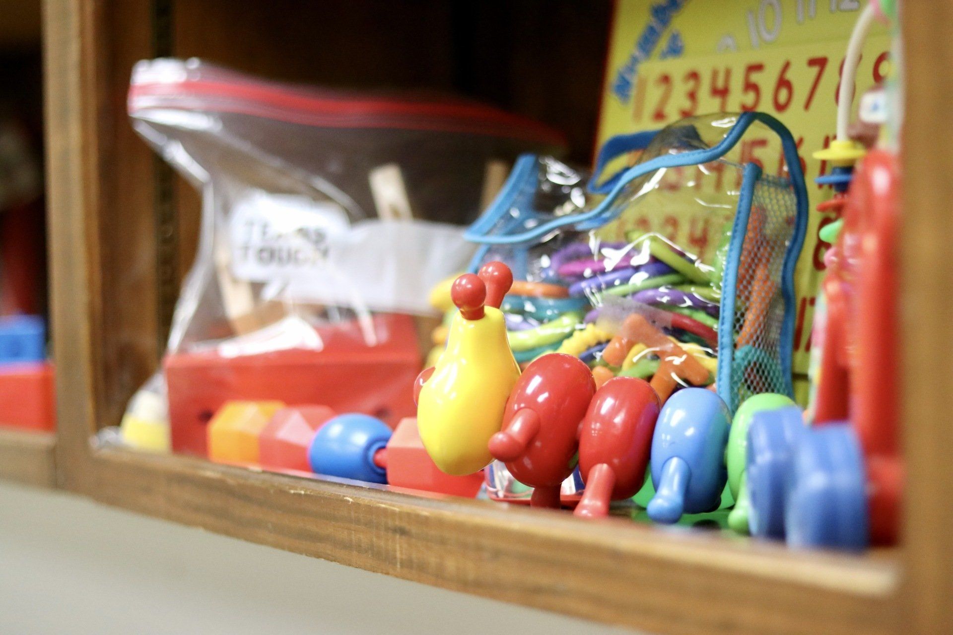 a bunch of colorful toys are sitting on a wooden shelf .