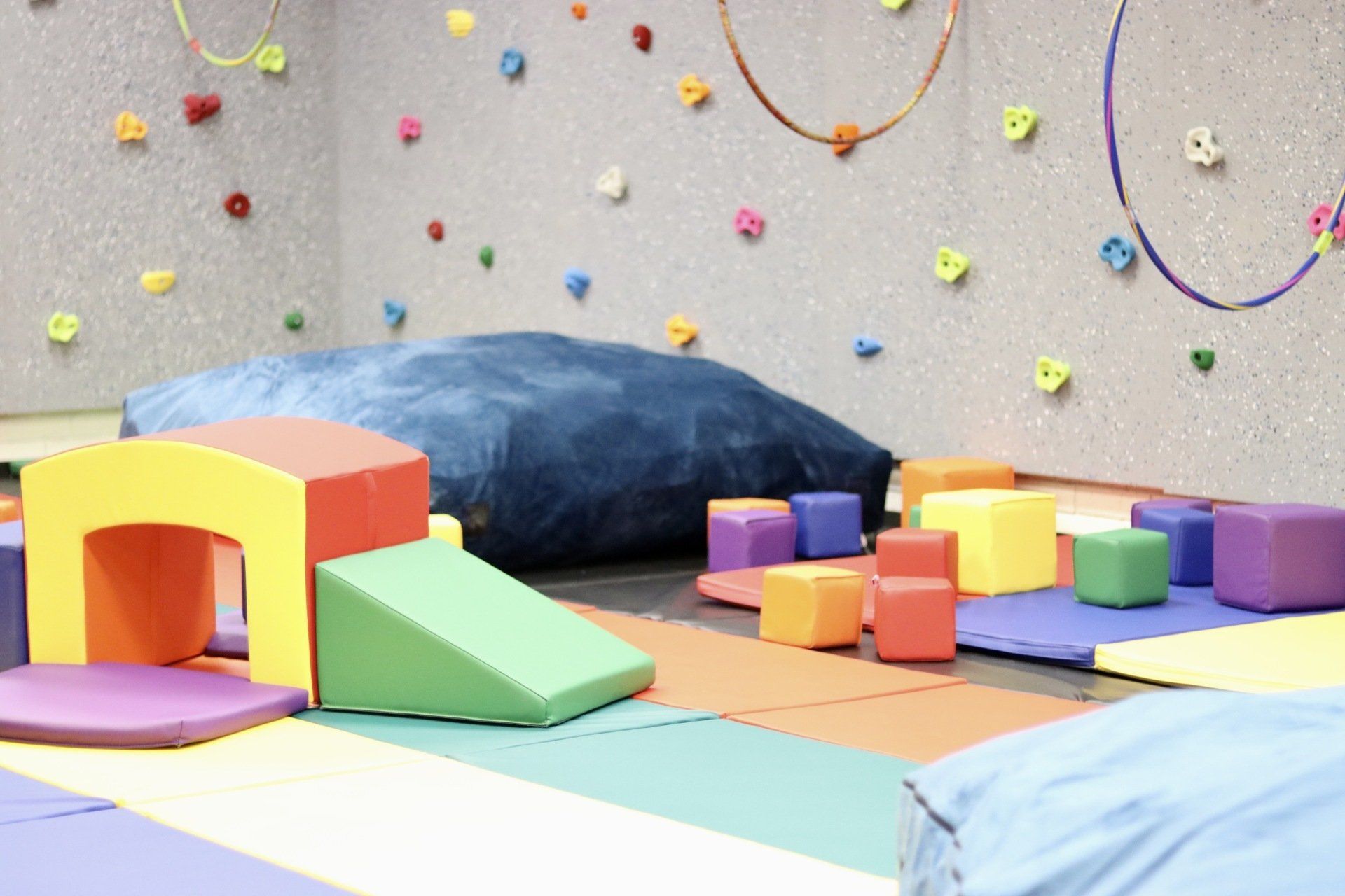 a room filled with colorful toys and a climbing wall .