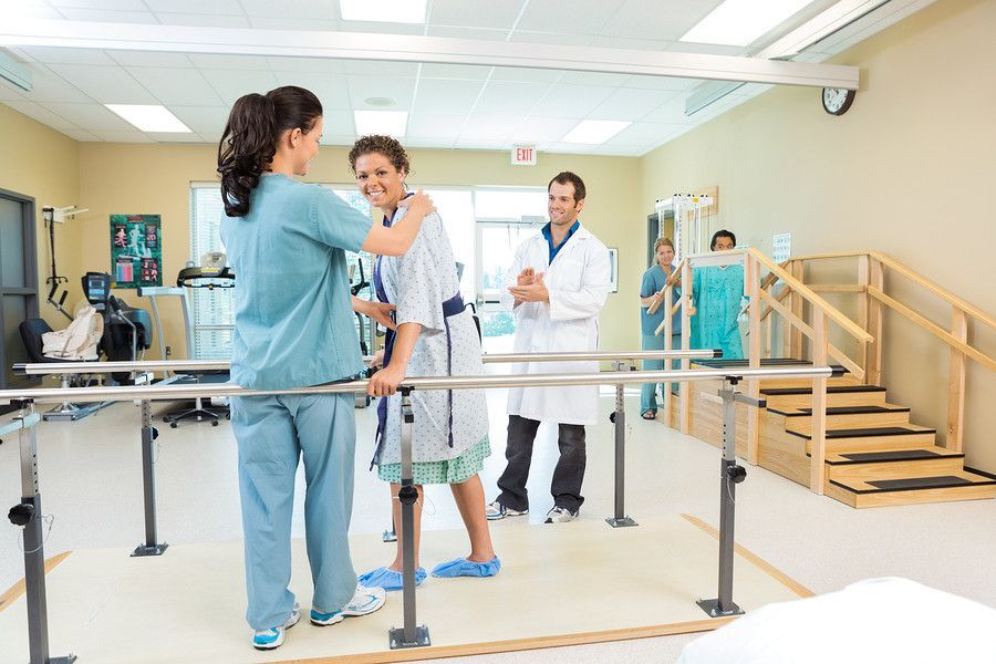 a nurse is helping a patient walk on parallel bars in a hospital .