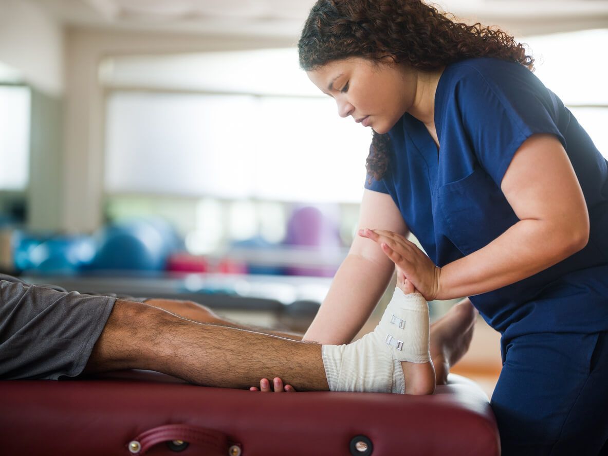 a nurse is wrapping a patient 's leg with a bandage .