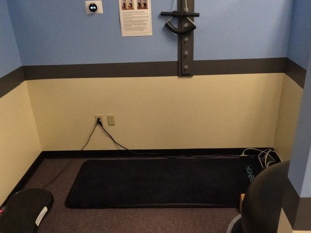 A corner of a room with a black mat on the floor