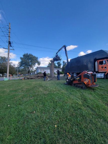 Orange farm equipment on a grassy field near a building under a blue sky