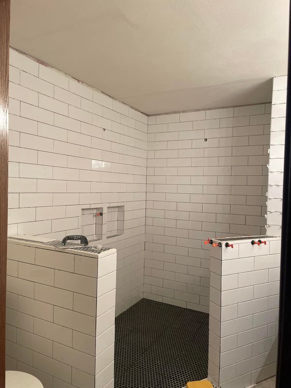 A bathroom with white tiles and a toilet.