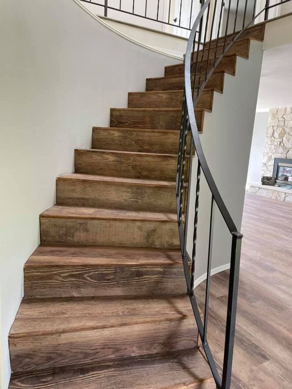 A spiral staircase with wooden steps and a metal railing in a house.