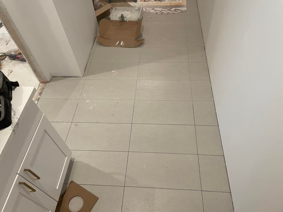 A hallway with white tiles and a cardboard box on the floor.