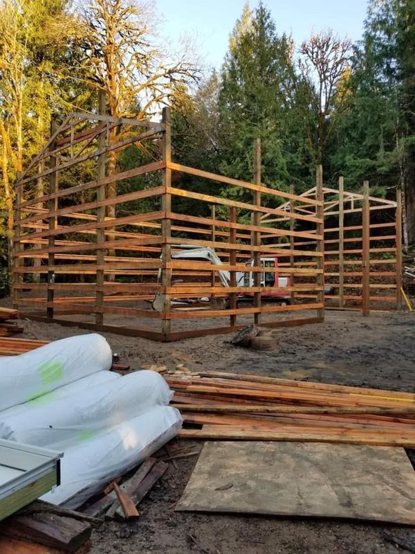 A large wooden structure is being built in the middle of a forest.