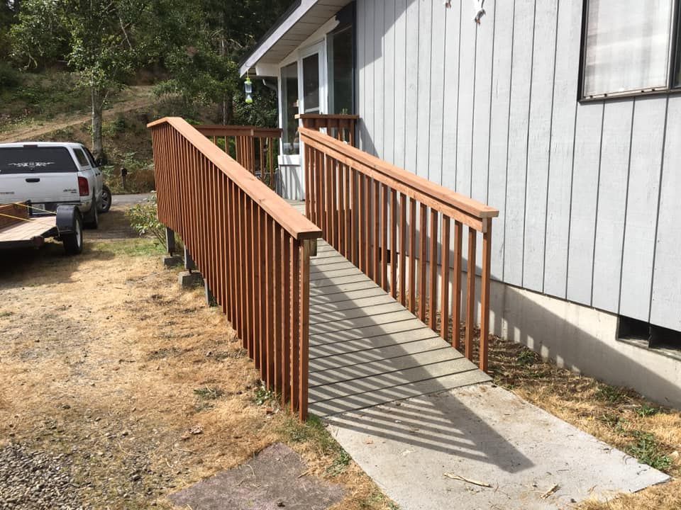 A white truck is parked next to a wooden ramp leading to a house.