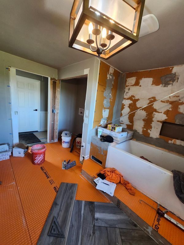 A bathroom under construction with a tub and a chandelier hanging from the ceiling.