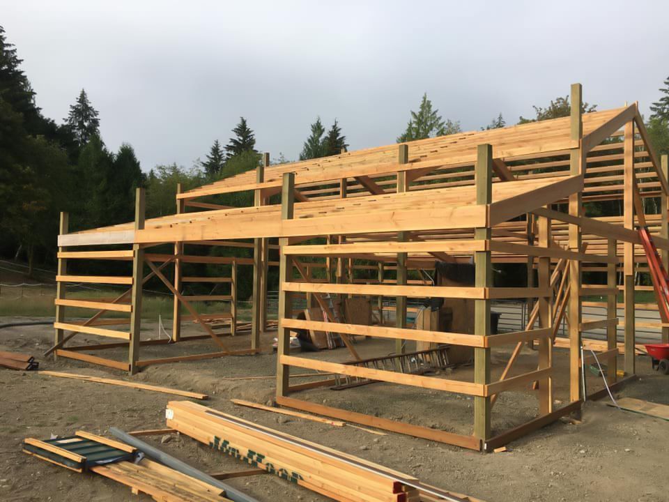 A large wooden structure is being built in a dirt field.