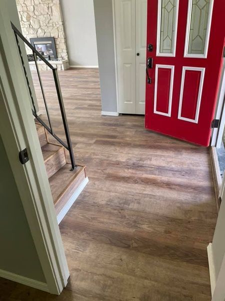 A red door is open in a hallway next to stairs.