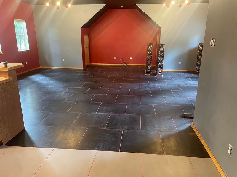 A large empty room with a tiled floor and a red wall.