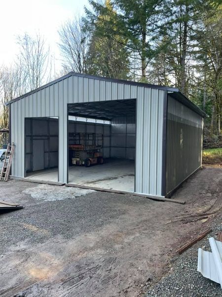 A metal garage is being built in the middle of a dirt road.