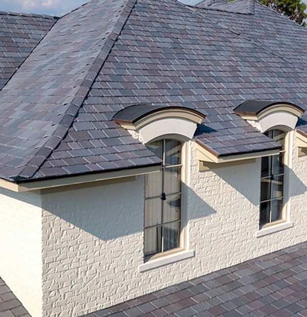 A white house with a slate roof and arched windows