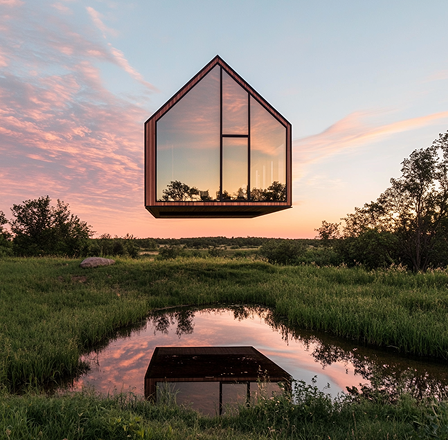 A house with a lot of windows is floating in the air over a pond.