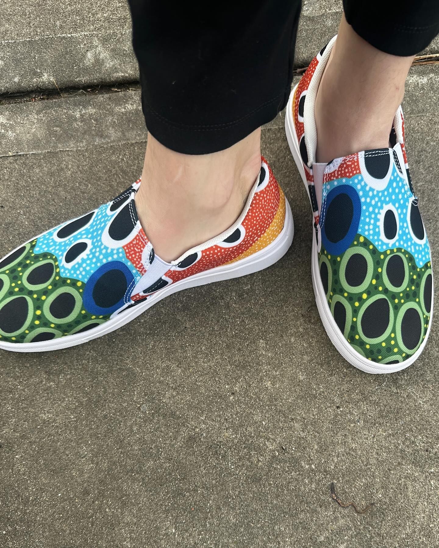 A person wearing a pair of colorful shoes with circles on them