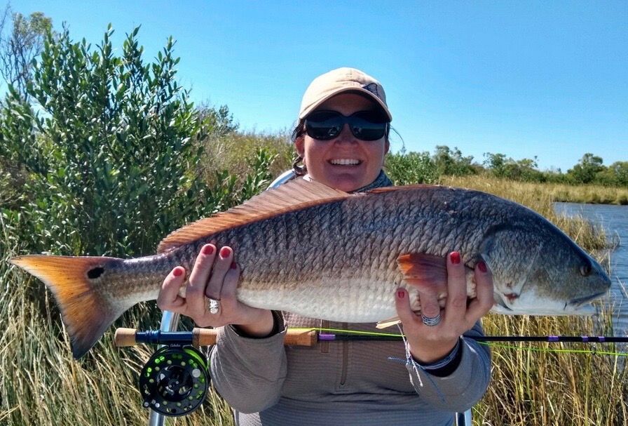 A woman is holding a large fish in her hands