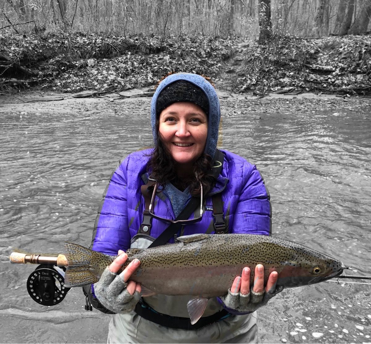 A woman in a purple jacket is holding a large fish