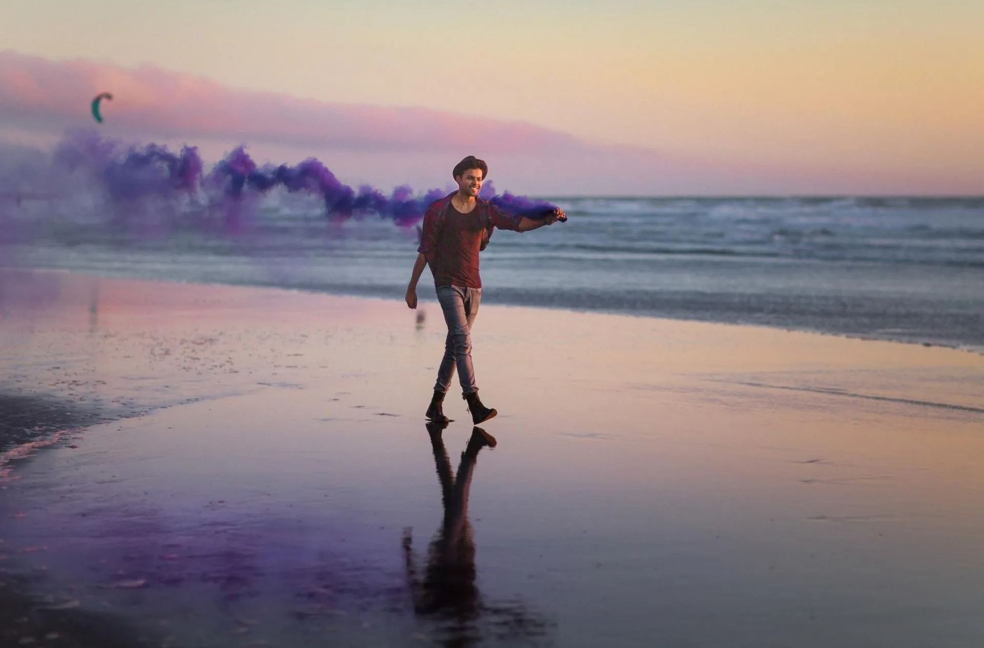 A man is walking on a beach with purple smoke coming out of the water.