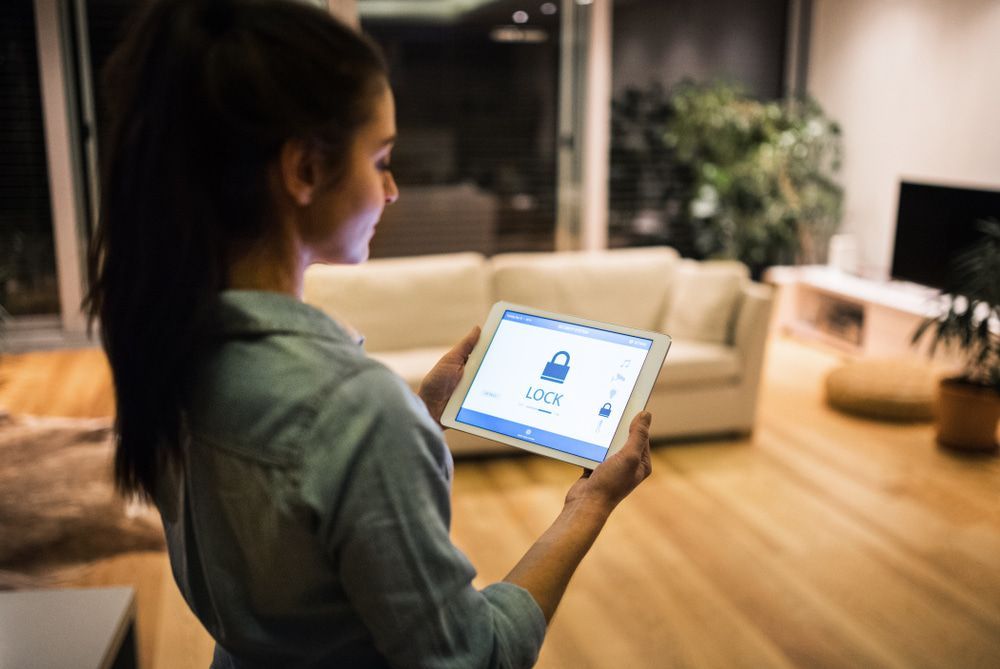 Woman Holding A Tablet With Smart Home Screen — Alarm Monitoring in Southern Highlands, NSW