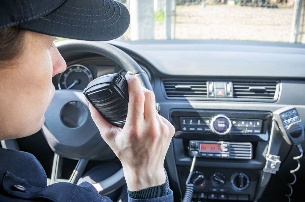 Security officer in a patrol car holding a radio for communication — Alarm Monitoring in Moss Vale, NSW