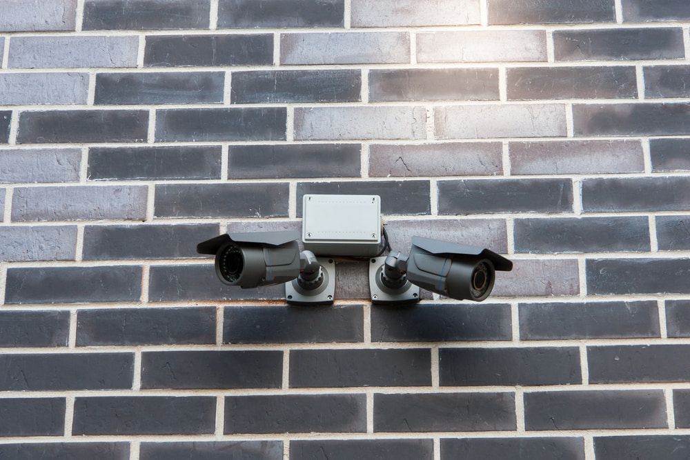 Two security cameras positioned on a house, providing surveillance from different angles — Alarm Monitoring in Moss Vale, NSW