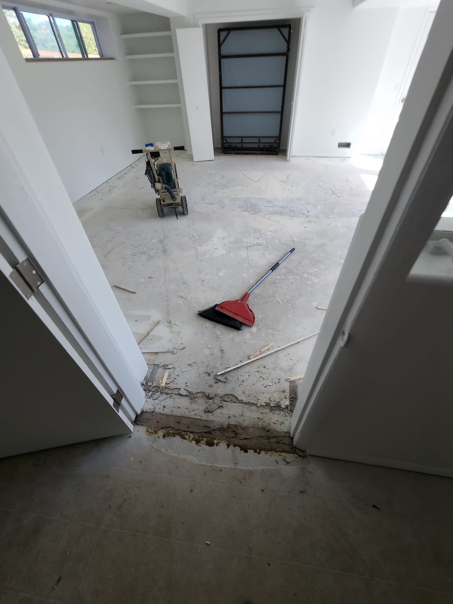 A room with a broom and a machine on the floor.