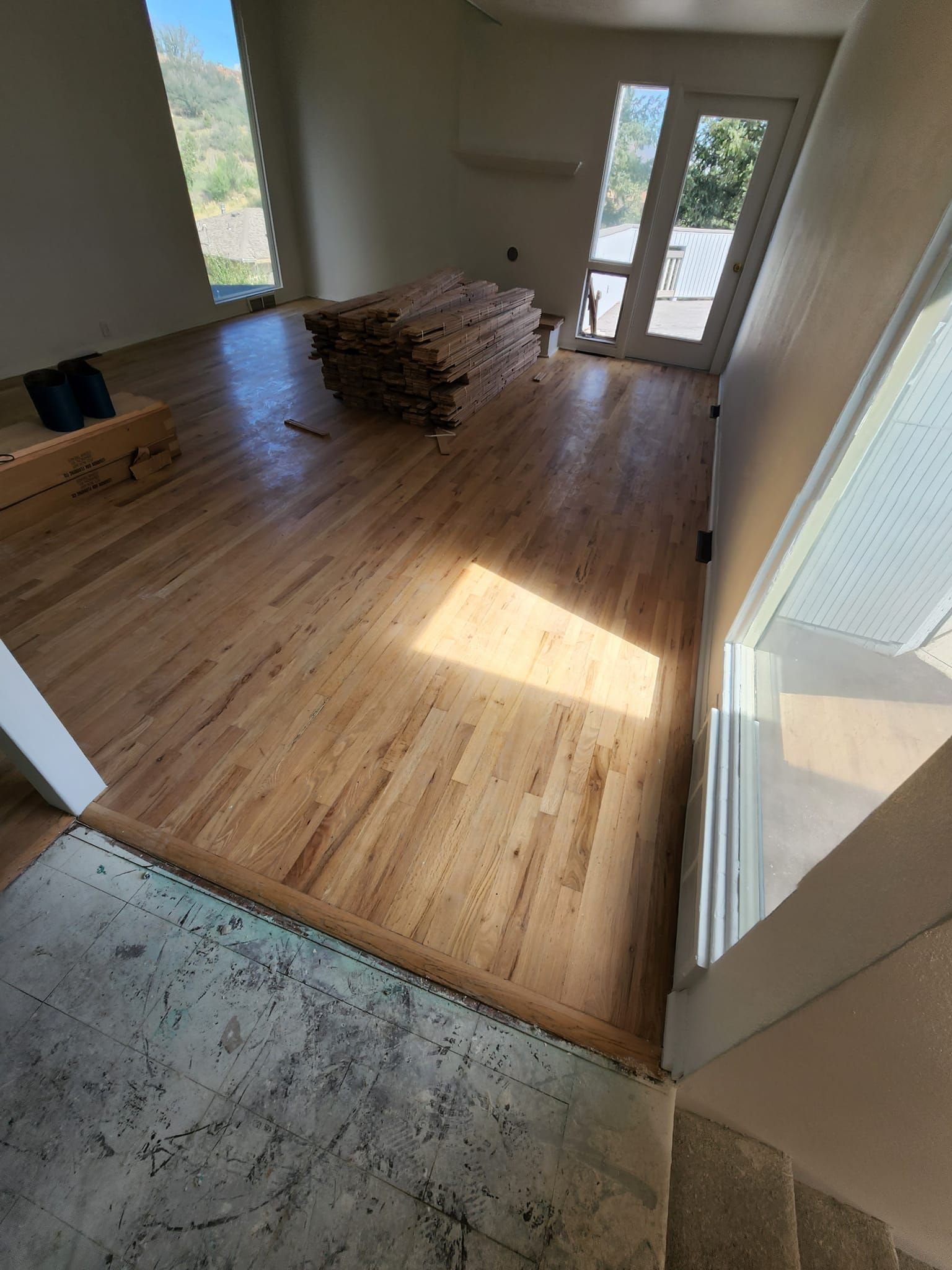 A living room with hardwood floors and a stack of wood in the middle of the room.