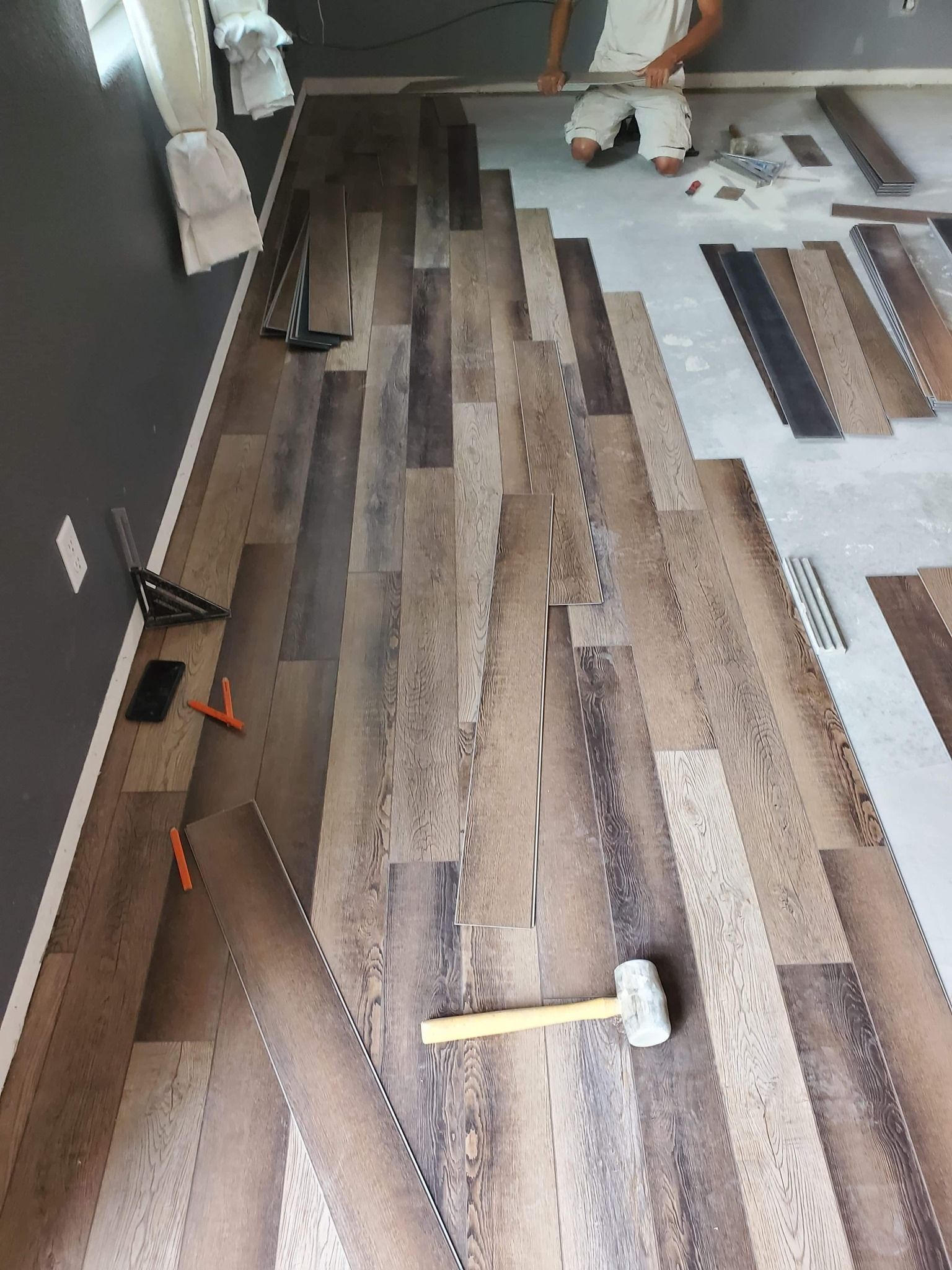 A man is laying a wooden floor in a room.