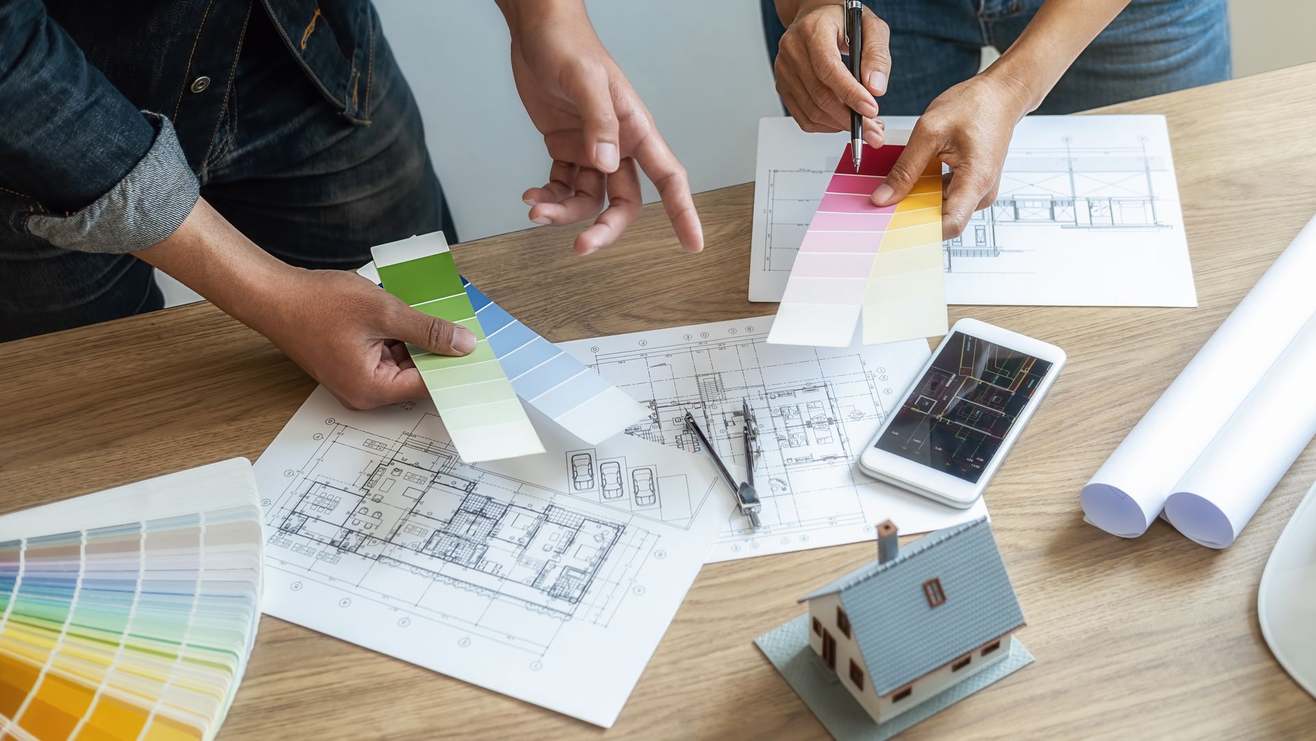 A group of people are sitting at a table looking at paint samples.