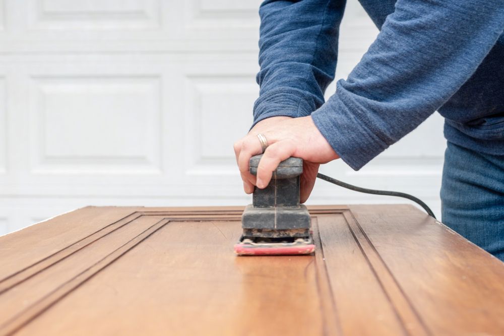 A person is sanding a wooden surface with a sander.