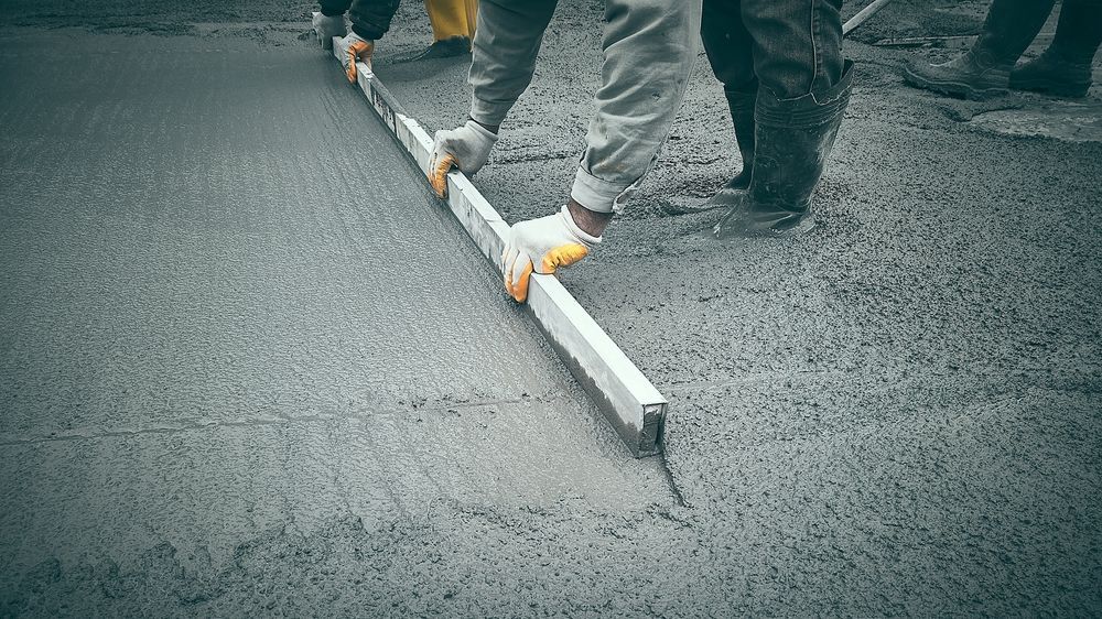 A group of construction workers are leveling concrete with a level.