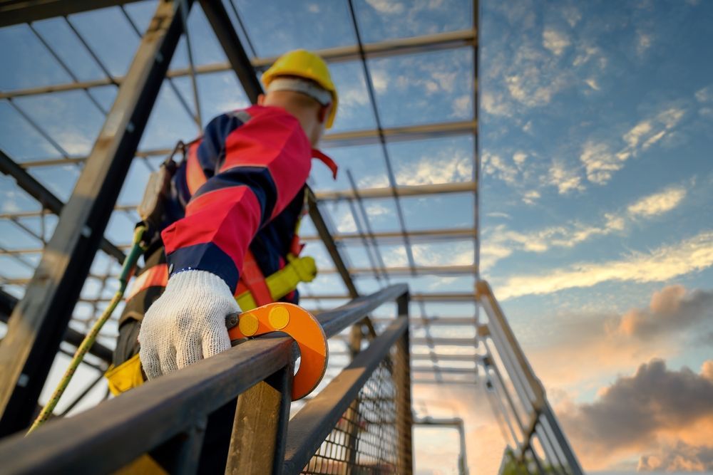 A construction worker is climbing a metal structure.