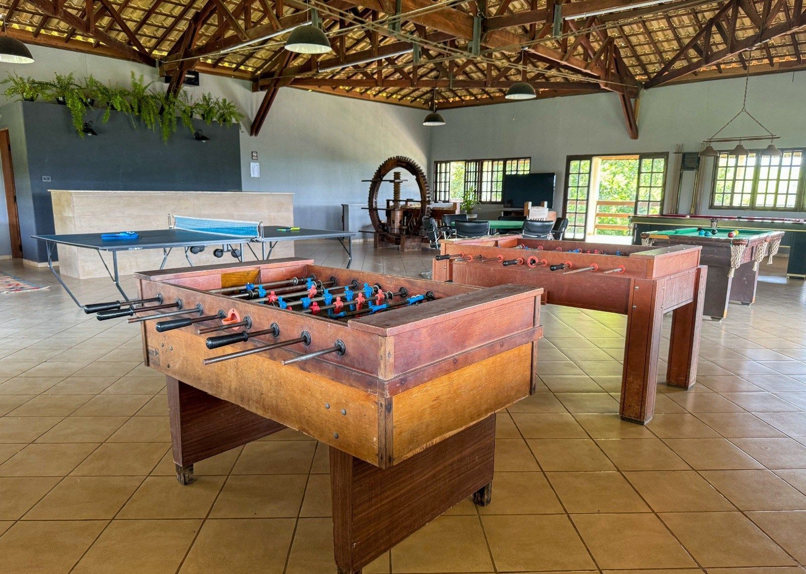 Mesas de pebolim em uma sala de recreação com mesas de bilhar e mesa de pingue-pongue.