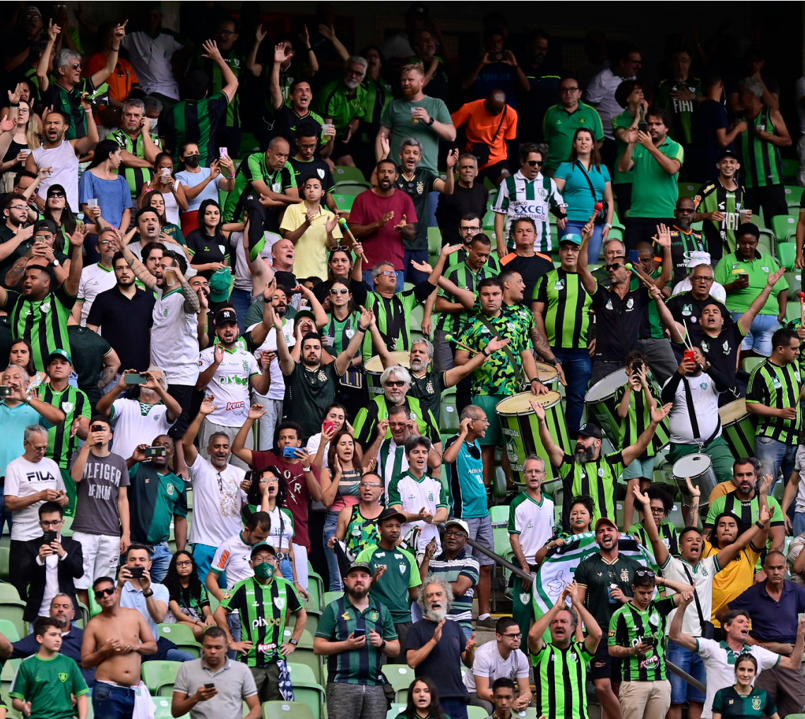 Uma multidão de pessoas com camisas listradas verdes e pretas está em um estádio