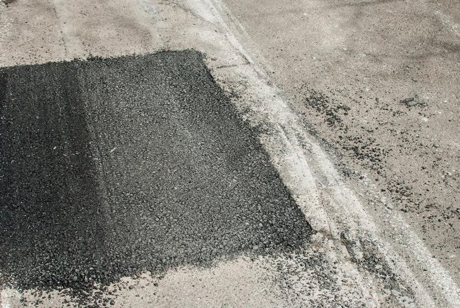 Cracked Asphalt Road Surface And Repair Patch Closeup — Bitumen Services in Darwin, NT