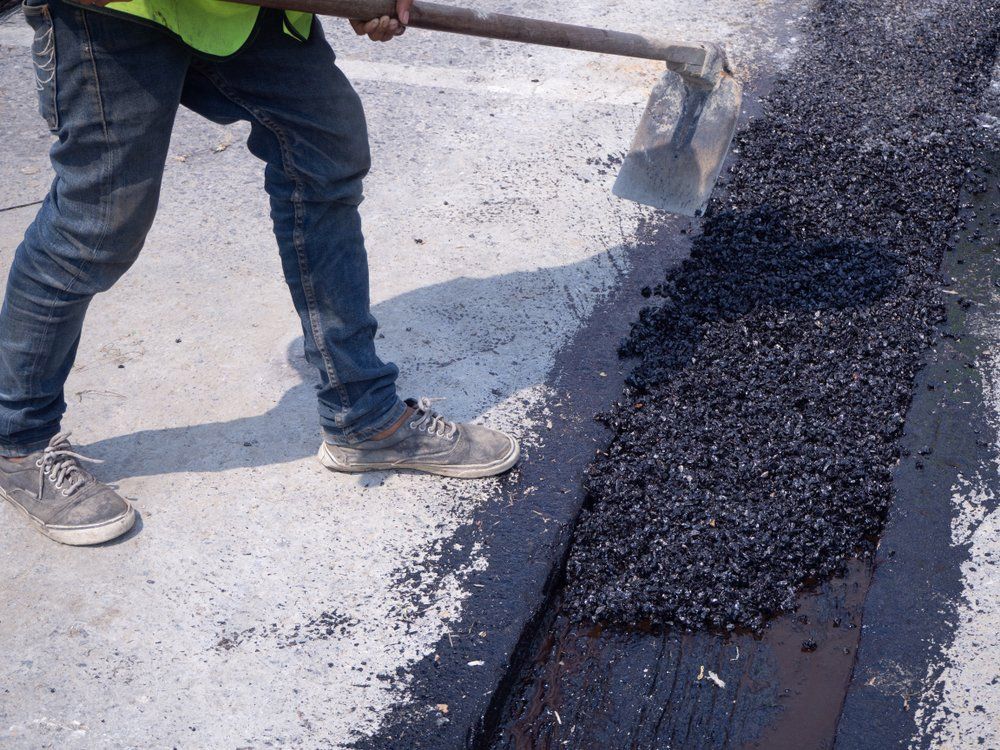 Worker Use Vibratory Plate Compacting Asphalt At Road Repair — Bitumen Services in Darwin, NT