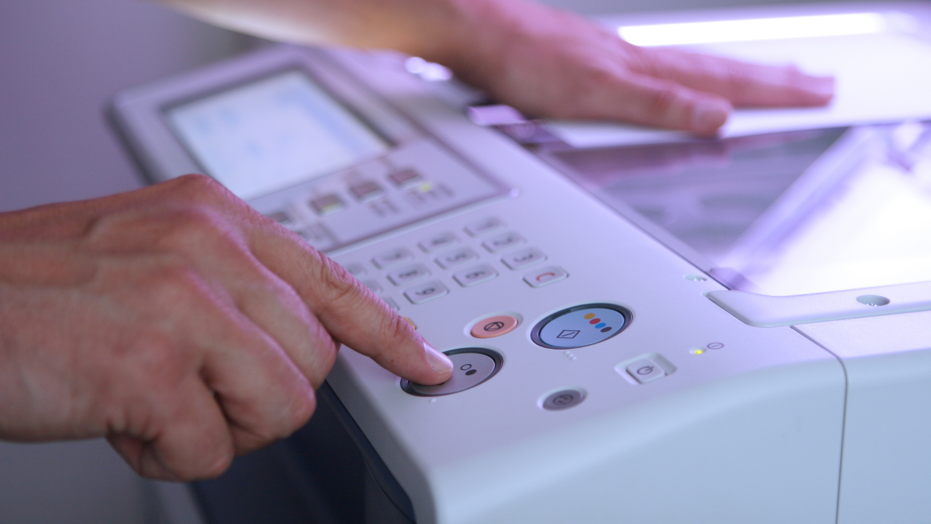 Person's hand pressing a button on a white photocopier.
