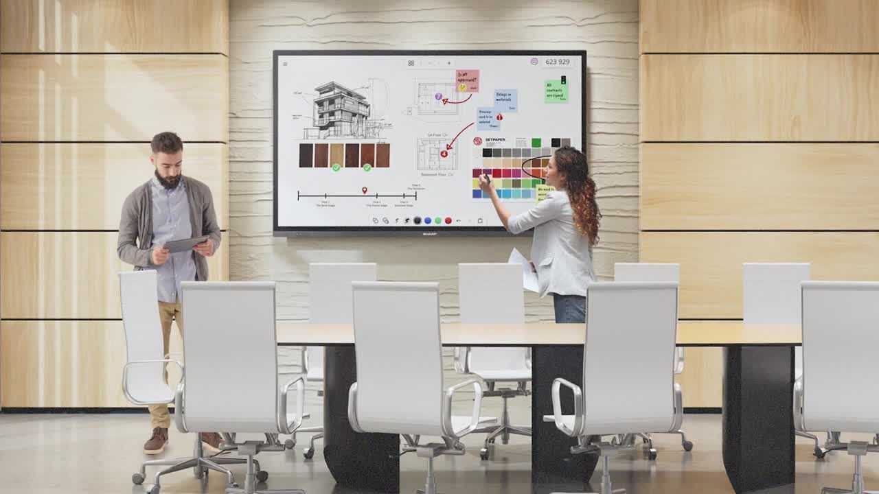 Teacher and student at a classroom screen, pointing at a map of the United States. Students watch.